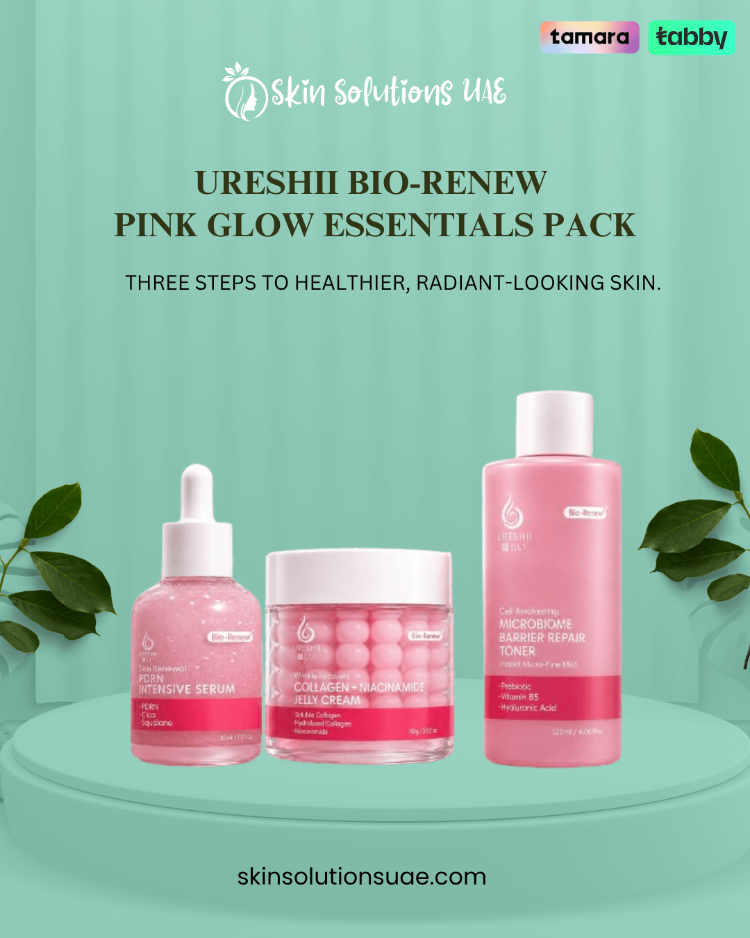 Three skincare products from Ureshii Bio-Renew Pink Glow Essentials Pack are displayed on a mint green pedestal. The set includes a serum in a dropper bottle, a collagen-boosting cream jar, and a toner in a tall bottle.